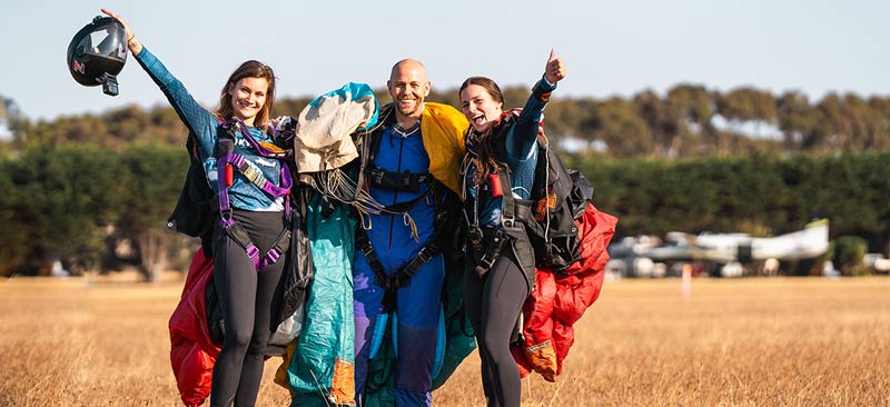 Skydiving student posing with AFF instructors after a skydive