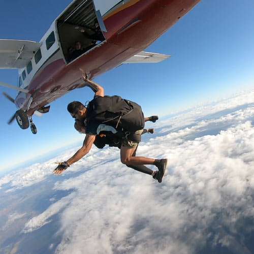 skydivers exiting plane over airlie beach