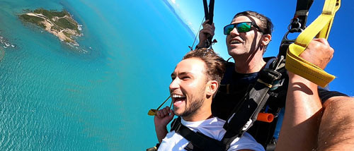 Tandem skydiving passenger and instructor flying a parachute over Airlie Beach Whitsundays QLD Australia