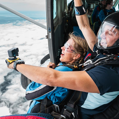 Skydiving instructor holding a selfie-cam about to jump out with tandem passenger