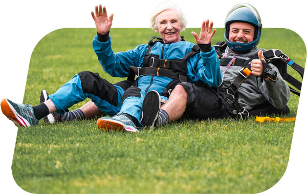 Old woman smiling with skydiving instructor after her skydive
