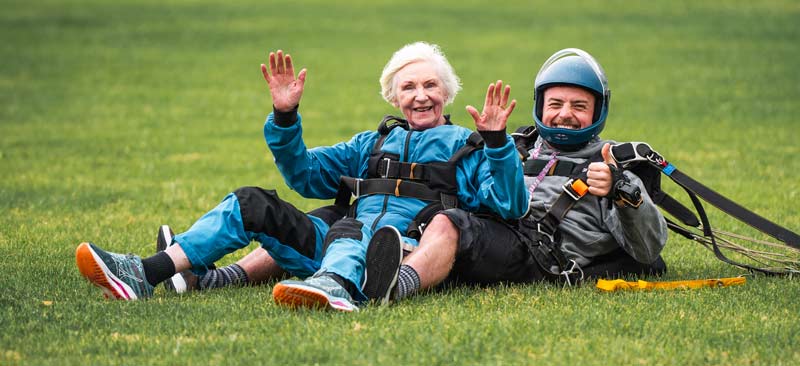 Old woman smiling on the ground after a skydive