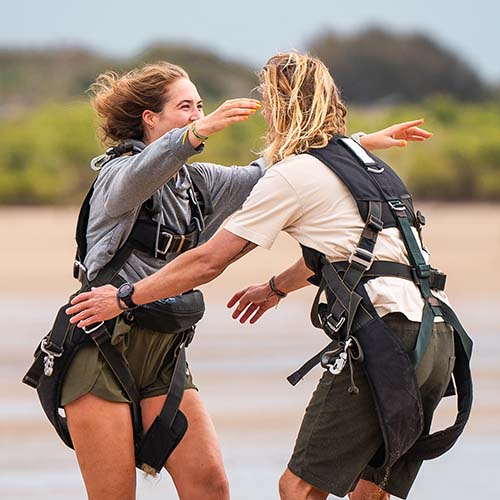 skydiving customers hugging after landing in Airlie Beach
