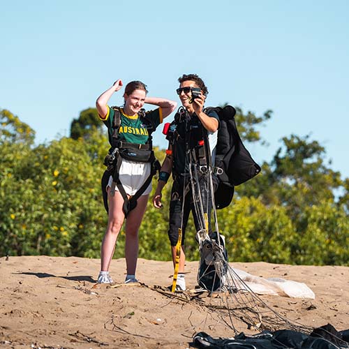skydiving instructor filming customer on the beach in Airlie Beach