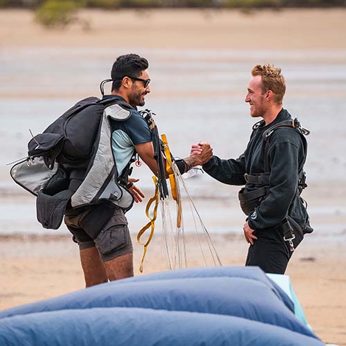 Skydiving instructor and customer shaking hands after landing on the beach in Airlie Beach