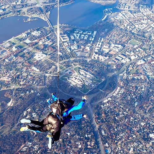 Tandem skydiving pair in freefall over Canberra with Parlamient House in the background