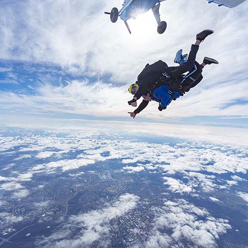 Tandem skydiving instructor and customer exiting plane