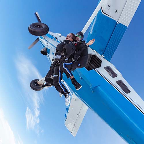 Tandem skydiving instructor and customer exiting plane
