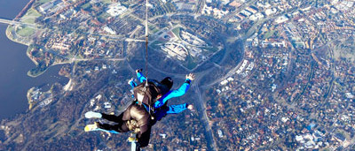Tandem skydiving pair in freefall over Canberra with Parlamient House in the background