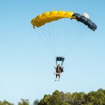 Tandem skydiving instructor and customer landing on the beach