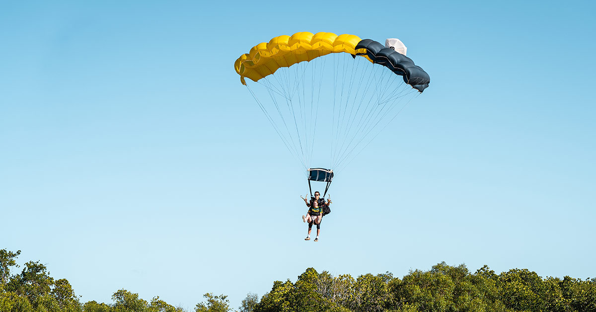 Tandem skydiving instructor and customer landing on the beach