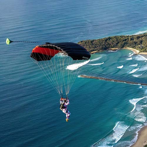 Licensed skydiver flying parachute over Moruya beach