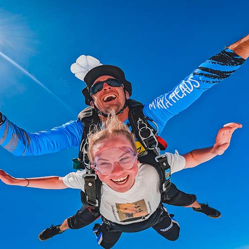 Tandem skydiving over Moruya's blue skies, instructor and excited student in freefall