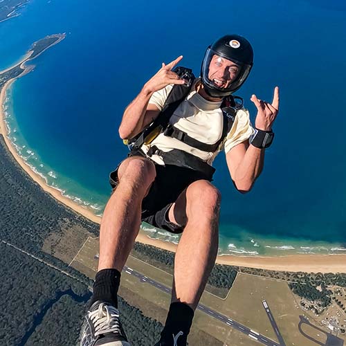 Skydiver exiting plane with coastline in the background