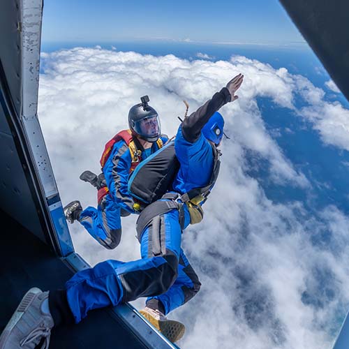 Two skydivers in freefall against blue sky and clouds