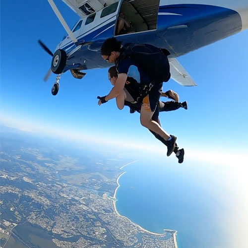 tandem skydiving pair exiting plane over Caloundra