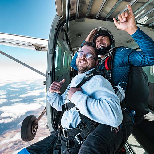 Excited skydivers prepare to exit an aircraft high above the Great Ocean Road coastline
