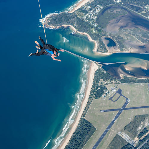 skydiving tandem pair freefalling over the ocean in Moruya
